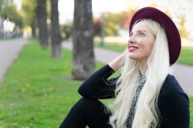 Ağaçların yanındaki parkta mutlu bir sarışının portresi. Bakış açısı