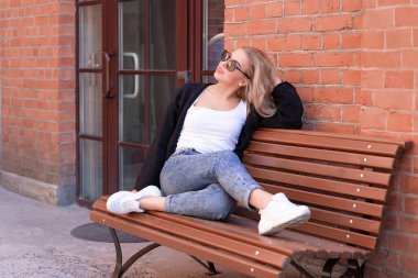 Güzel genç şehir kadını bankta oturuyor.