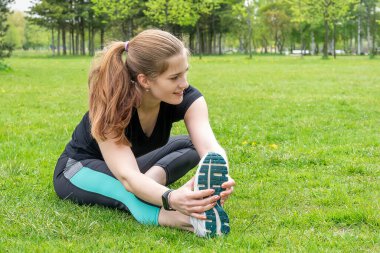 Güzel kız evin yakınındaki bir parkta spor yapmadan önce ısınıyor..