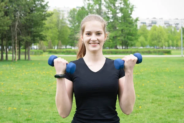 Athletic girl posing with dumbbells in hands before training.
