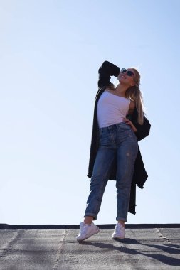 Çatıda poz veren güzel bir sarışın. Bir eliyle belini tutuyor. Saçımdaki ikinci el. Parlak güneşli bir gün