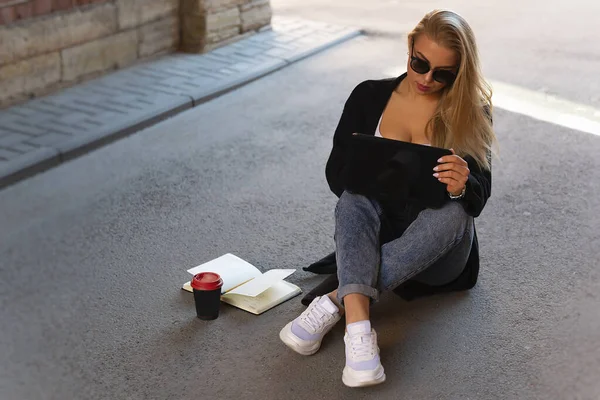 Güneş gözlüklü seksi sarışın kavurucu güneşten gölgede saklanırken bilgisayarda çalışıyor..