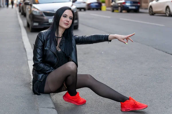 Yolda oturan bir kız taksiye biner. Ön görünüm