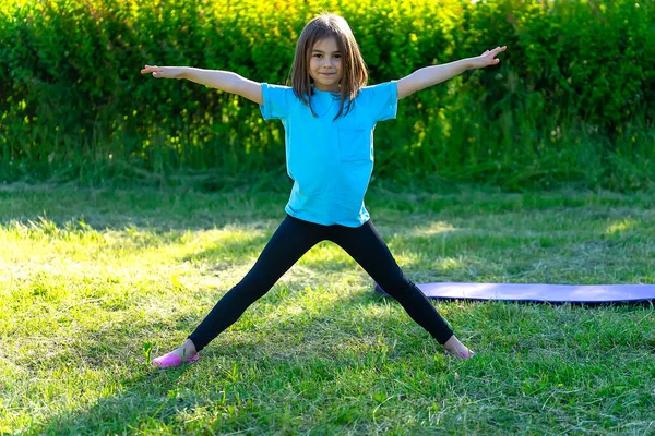 Little girl doing sports in the park. Warm up before training