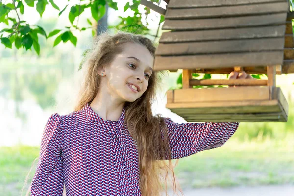 Kız, parkta bir yalakta kuşları besler. Ön görünüm