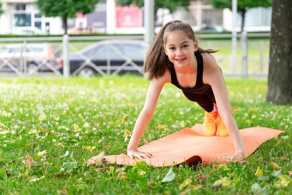 Jimnastikçi kız kompleks egzersizler yapmadan önce çim parkında ısınıyor. Fotoğraf serileri