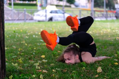 Okul çağında bir kız çimlerin üzerindeki parkta jimnastik yapıyor. Fotoğraf serileri