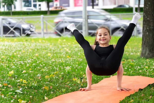Okul çağında bir kız çimlerin üzerindeki parkta jimnastik yapıyor. Fotoğraf serileri