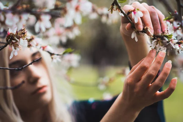 Junge Blonde Frau Steht Blühenden Baum Und Berührt Blüte — Stockfoto