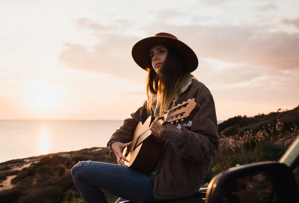 Kvinna Sitter Bilen Och Spelar Gitarr Kusten Vid Solnedgången — Stockfoto