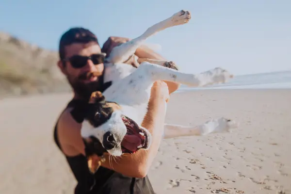 Мужчина играет с собакой на пляже — стоковое фото