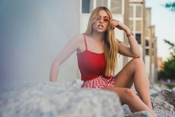 Jovem Mulher Shorts Vermelhos Top Tanque Sorrindo Enquanto Sentado Rochas — Fotografia de Stock