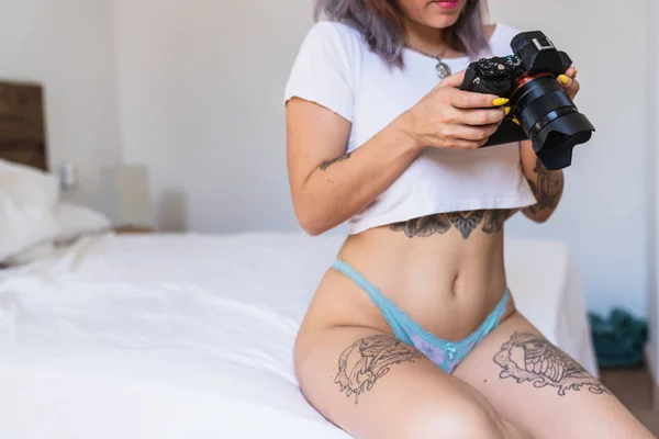 Dövmeli Kadın Külot Yatağın Üstüne Oturan Modern Kamerada Fotoğraflarına Bakmaktan — Stok fotoğraf