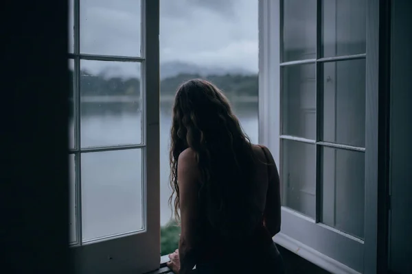 Kobieta Patrząca Przez Okno Pokoju — Zdjęcie stockowe