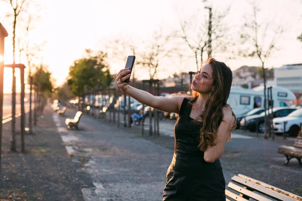 Atrakcyjna Pani Czarnej Sukni Ręką Włosy Biorąc Selfie Ulicy Zachodzie — Zdjęcie stockowe