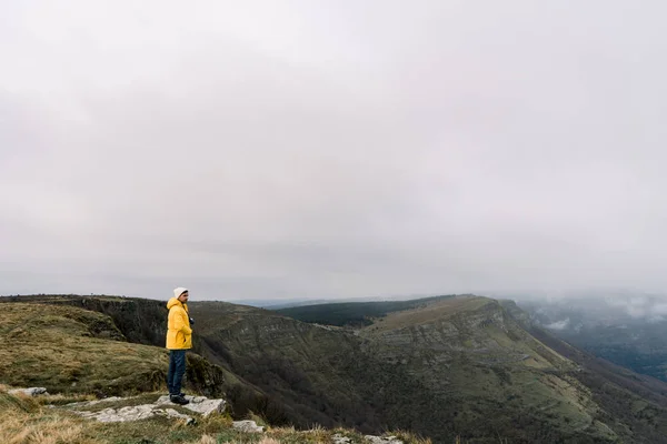 Вид Сбоку Парня Желтом Пальто Шляпе Стоящего Вершине Горы Облачного — стоковое фото