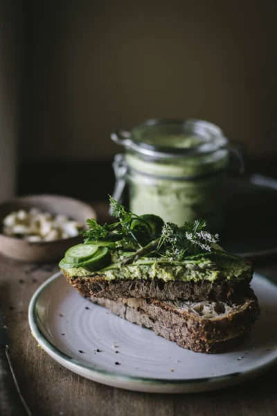 用绿色腰果 黄瓜片和罐子放在木板上的烤面包 — 图库照片