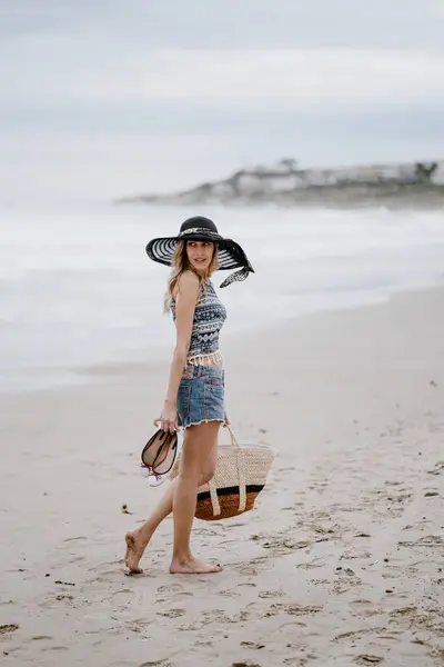 Mulher Atraente Chapéu Preto Segurando Saco Praia Sapatos Enquanto Desfruta — Fotografia de Stock