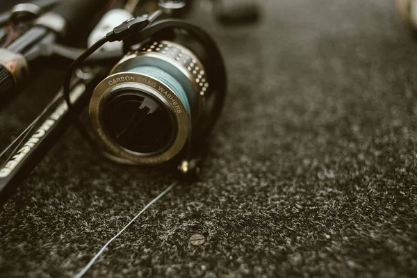 小石の釣りのための黒いカバーと青い強いラインと光沢のある釣りリールと釣り竿 — ストック写真