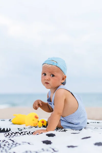 彼のゴム製のアヒルの横にビーチでキャップを持つ赤ちゃんの後部ビュー — ストック写真