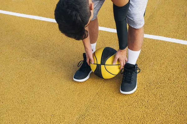 Ung Man Böja För Bollen Medan Spelar Basketplan Utomhus — Stockfoto