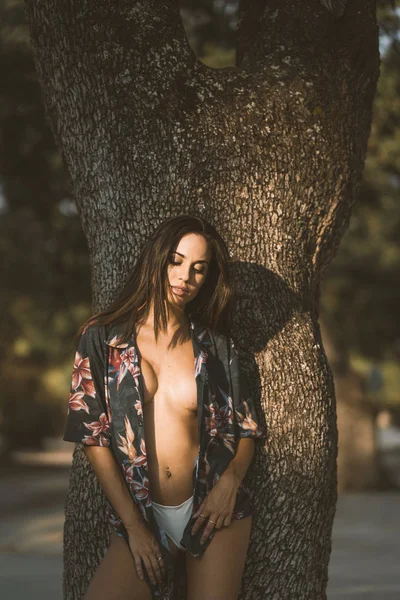 Sexy beautiful woman gazing and resting beside tree at park — Stock Photo, Image