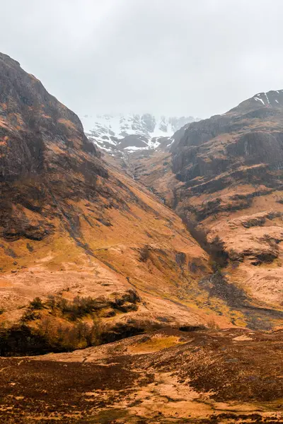 苏格兰高地多云的春天 一条狭窄的弯道在多山的丘陵地带蜿蜒曲折 干枯的草丛中穿行 — 图库照片