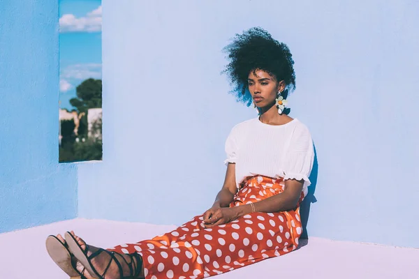 Чорна жінка сидить на барвистій терасі геометричного будинку. — стокове фото