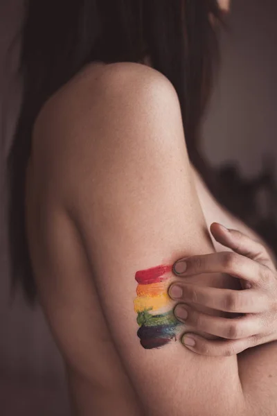 Atractiva mujer desnuda cubriendo el pecho y dibujando símbolo LGBT - foto de stock