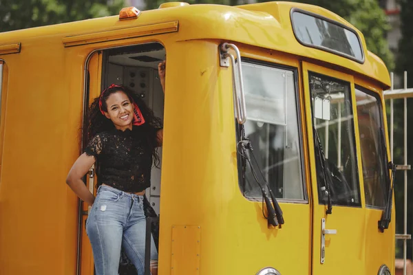 Young cheerful beautiful hispanic woman standing on yellow train in drivers cabin in Berlin looking at camera — Stock Photo