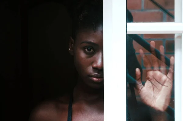 Upset black female standing behind window — Stock Photo