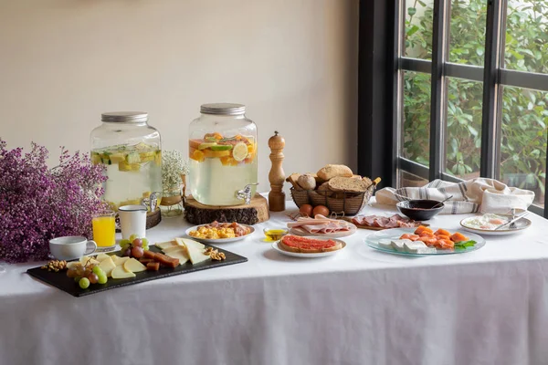 Vue latérale du dîner festif avec de savoureux fruits, des pâtisseries et des bancs de limonade élégants sur une table décorée de fleurs de lilas — Photo de stock