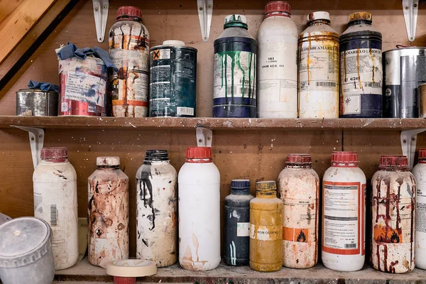 Colección de botellas y frascos multicolores de plástico y metal de productos químicos especiales para trabajos de carpintería en estantes de madera en un taller contemporáneo - foto de stock