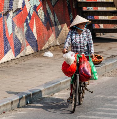 Kimliği belirsiz bir kadın, Hanoi, Vietnam 'da bisiklet sürüyor.