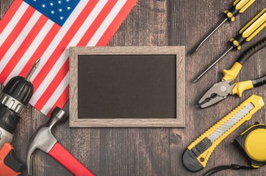 Fotoğraf çerçevesi ve siyah mockup.İnşaat araçları ve ahşap arka planda Amerikan bayrağı. İşçi Bayramı, 1 Mayıs.