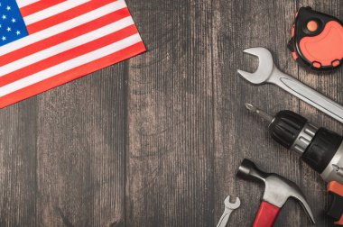 Tornavida, anahtarlar, çekiç, mezura ve ahşap arka planda Amerikan bayrağı. İşçi Bayramı, 1 Mayıs.