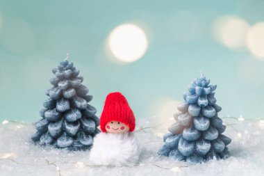 Noel arkaplanı, kart. Köknar ağacı şeklinde el yapımı mumlar ve karda bir kardan adam Bokeh 'li mavi bir arka planda..