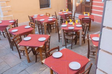 Geleneksel İtalyan kafesi akşam yemeği için hazırlanan masalar, kırsal sandalyeler ve renkli dekorlar. Akdeniz yaşam tarzında gastronomi, seyahat ve konukseverlik kavramları için mükemmel bir sahne..