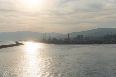 Endüstriyel limanı olan Ceneviz Körfezi üzerinde gün batımı manzarası. Seyahat, nakliye, enerji ve Akdeniz manzarası kavramı.