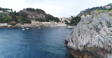 Hava kuş görünümü uçan uçurum büyük kıyı şeridi manzara geçmiş ve şaşırtıcı ve çapa için döşeme tekneler yat ile defne güzel mavi okyanus yaz tatil tropikal arka plan için Sicilya, 4k 50fps