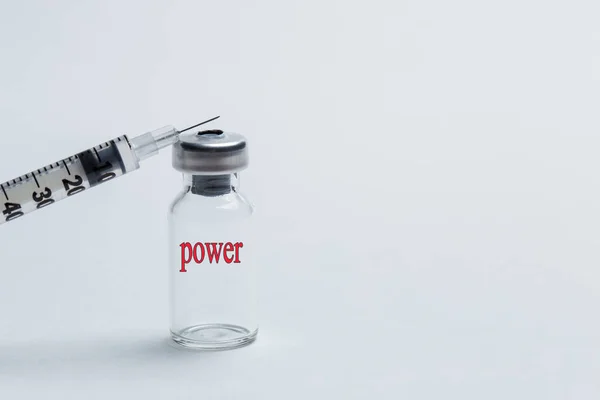 A syringe and a bottle for a vaccine with an inscription of power close up — ストック写真