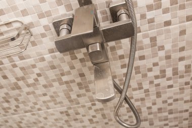 Banyoda su musluğu var. Yakın plan. Sert su. Kirli suyun musluğunda plaket var..