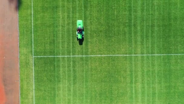 Un tosaerba sta tagliando un campo da calcio. Vista aerea in una giornata di sole. La fotocamera è in posizione verticale . — Video Stock