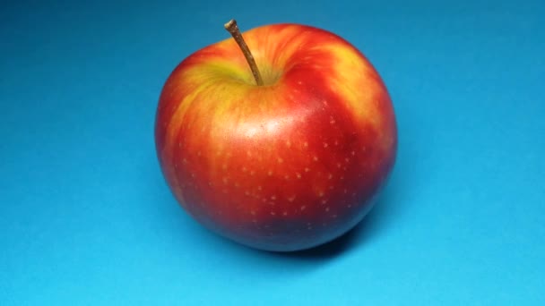 Czerwone jabłko na niebieskim tle zbliżenie. — Wideo stockowe