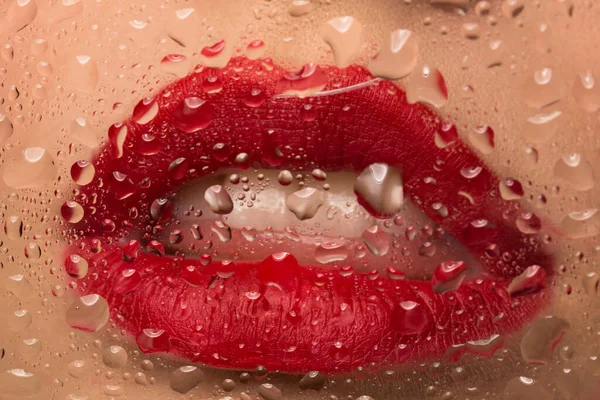 Labios con lápiz labial rojo de cerca. Gotas de agua en el vaso . — Foto de Stock
