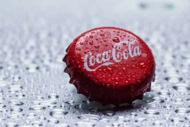 Klasik Coca-Cola kapağı yakın plan gri zemin üzerinde su damlaları ile.