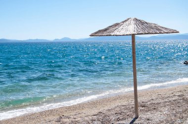 Boş sahilde bir şemsiye. Şemsiyeli bir deniz arka planı. Kopya alanı olan bir deniz manzarası. Seyahat ve turizm geçmişi.