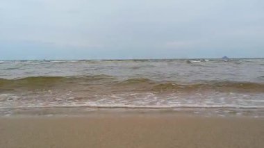 Akşamüstü kumlu sahilde beyaz köpüklü okyanus dalgaları