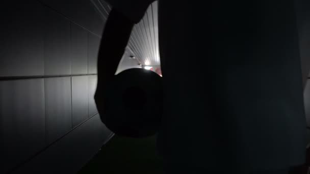 Dva hráče Fotbal jdou podél temným tunelem na fotbalové hřiště. Pohled z zadní