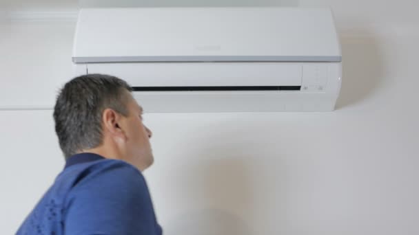 The man approaches the air conditioner and turns it on with the remote control — Stock Footage The man approaches the air conditioner and turns it on with the remote control Royalty Free Stock Video